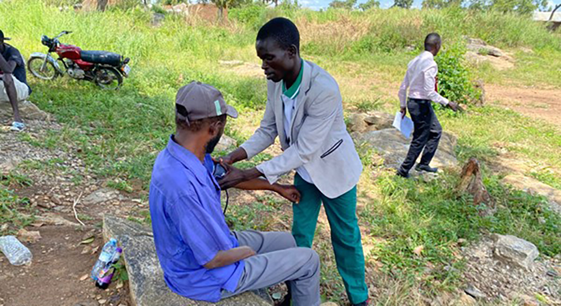 A village health team member performing blood pressure measurement at Bidi Bidi Settlement, Zone 1.