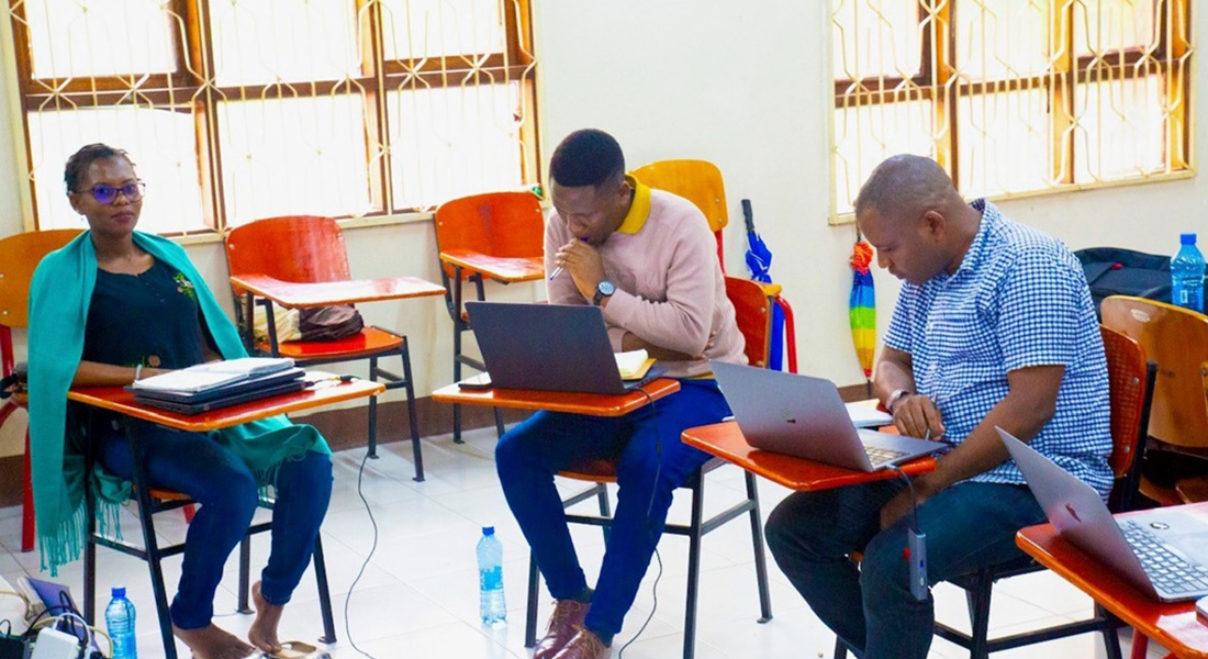 Three people sitting on chairs, and working on computers